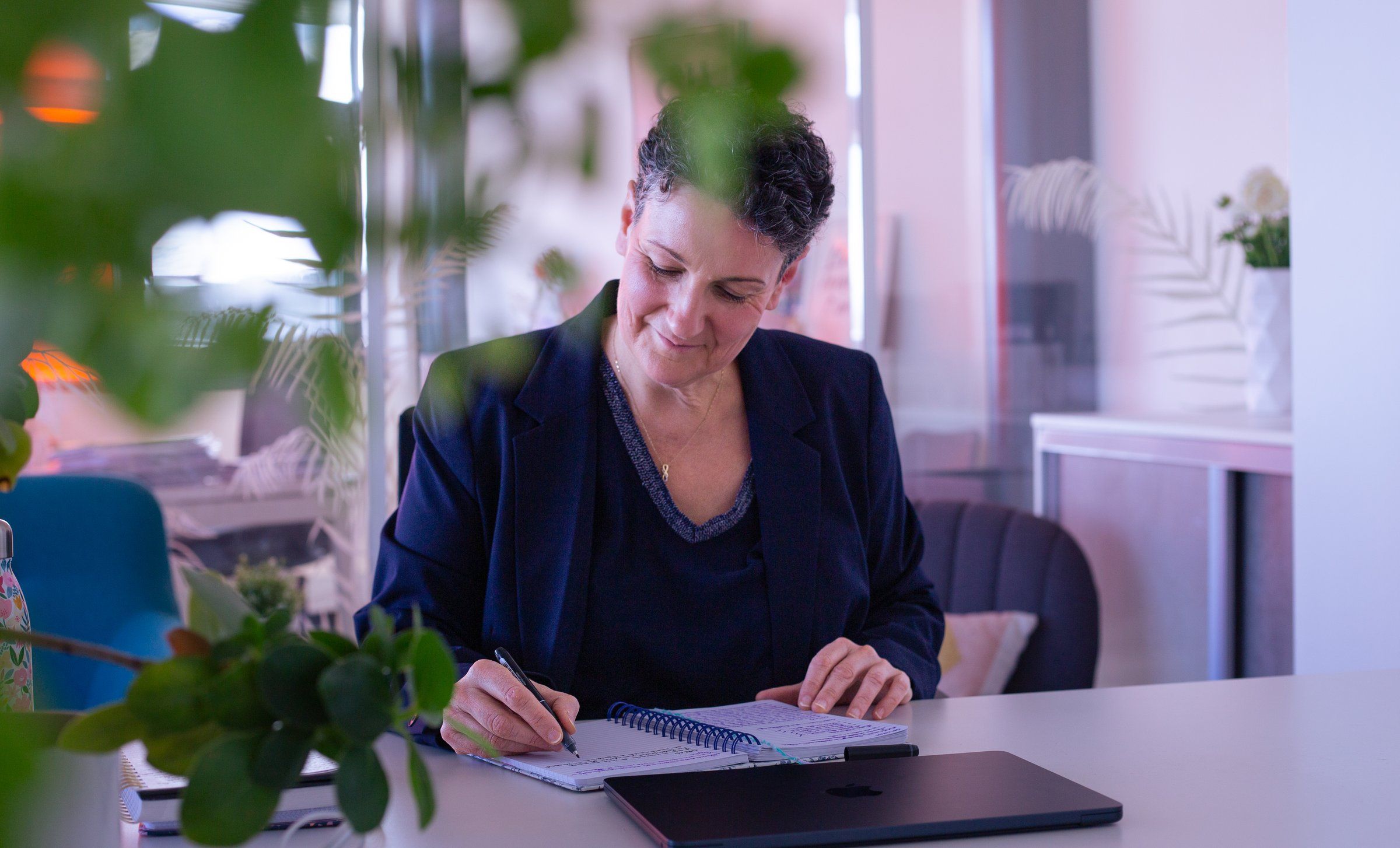 Marie-Laure Bourgeois rédige dans un carnet, à son bureau