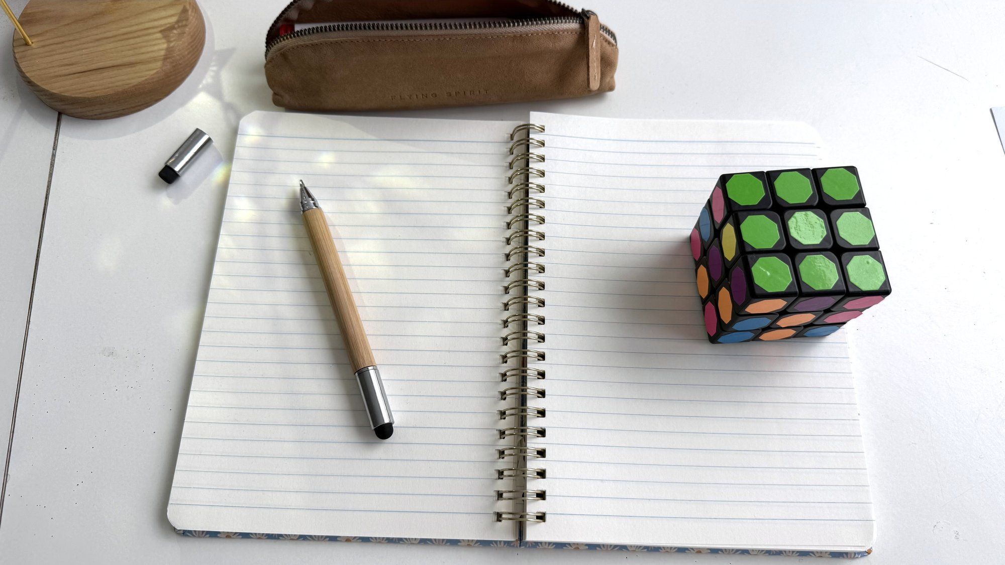 Un Rubik’s Cube posé sur un carnet ouvert, à côté d’un crayon